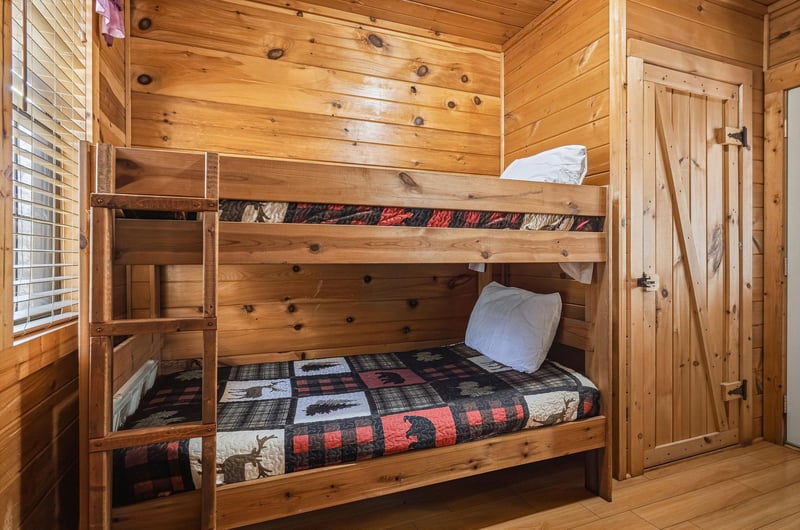 Cozy wooden bunk bed room with rustic charm and plaid quilts for your mountain getaway adventure.
