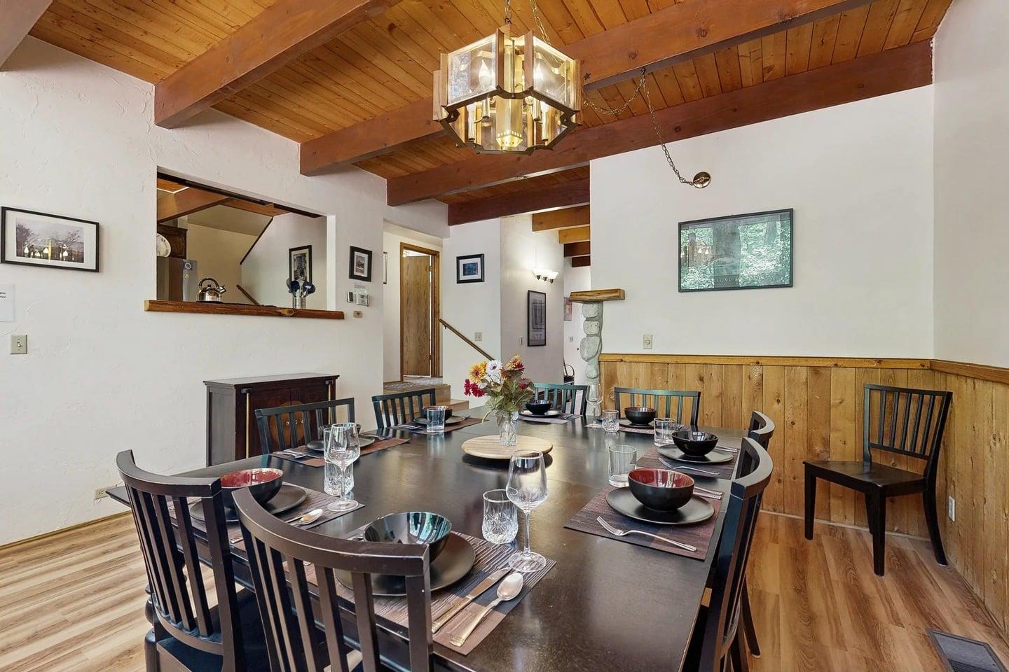 A wider look at the dining area, open to the loft and stairs beyond — the heart of the cabins openconcept living space.
