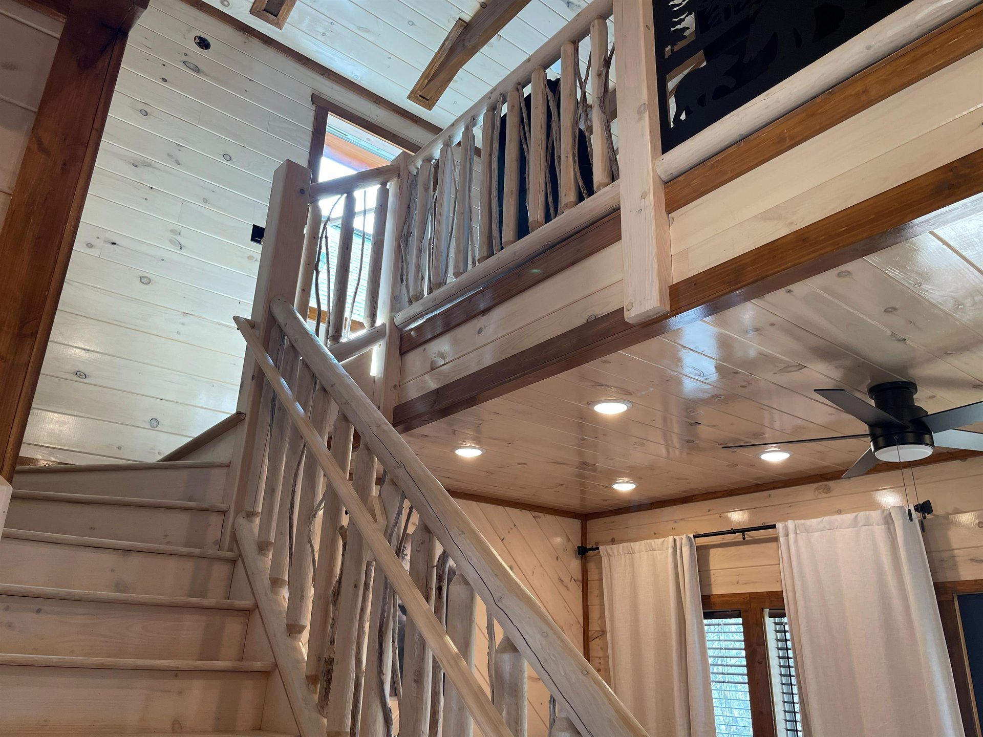Rustic wooden staircase leads to your cozy loft retreat, where natural pine beams and warm lighting create the perfect cabin atmosphere.