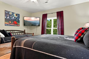 Unwind in your cozy bedroom with a plush bed, ceiling fan overhead, and a TV for your favorite shows. Natural light and nature views complete the peaceful retreat.