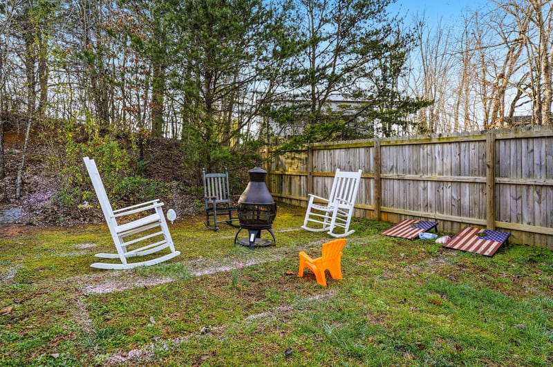 Your private backyard retreat awaits with cozy rocking chairs around a fire pit, perfect for evening relaxation and cornhole games.