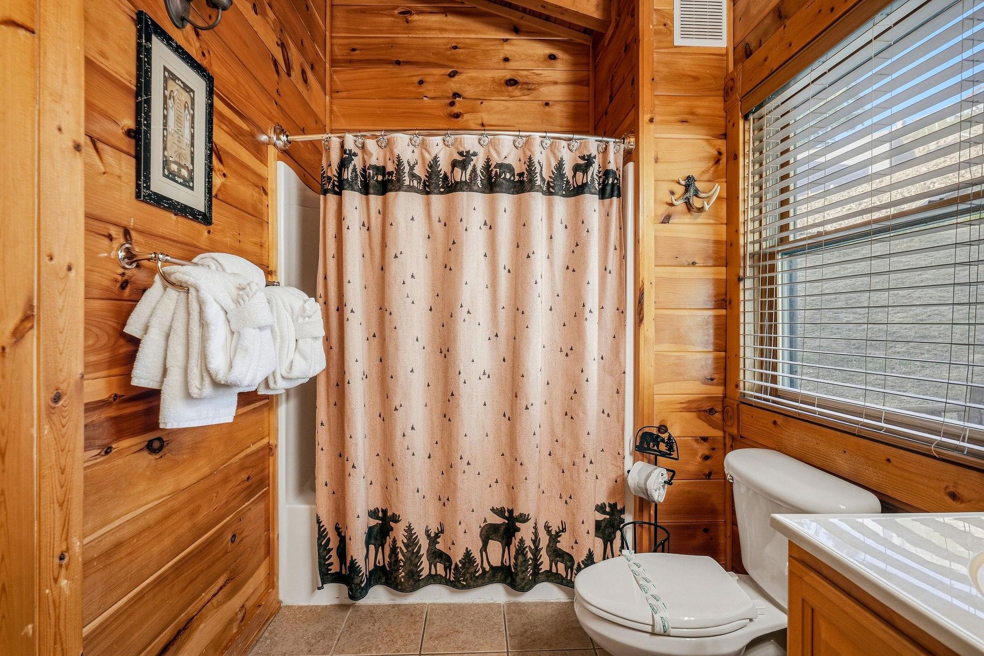 Step into your private bathroom with rustic charm, where fresh towels and woodland details await your relaxing mountain retreat.