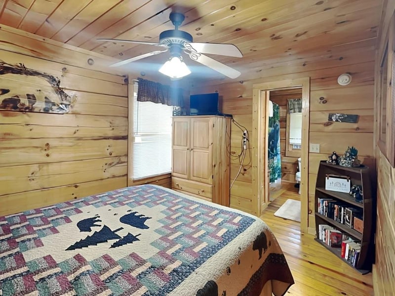 Your cozy cabin retreat awaits with rustic pine walls, a handcrafted quilt, and a ceiling fan to keep you comfortable yearround.