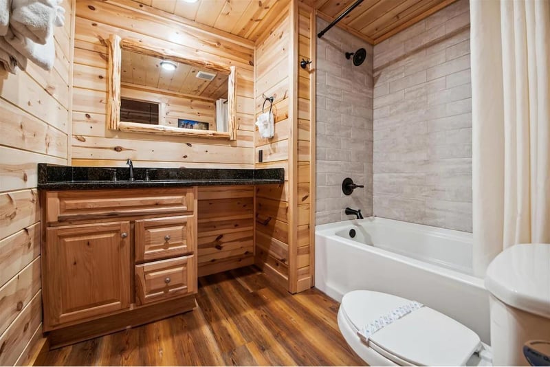 Your private cabin bathroom blends rustic charm with modern comfort, featuring warm wood walls and a soaking tub for relaxation.