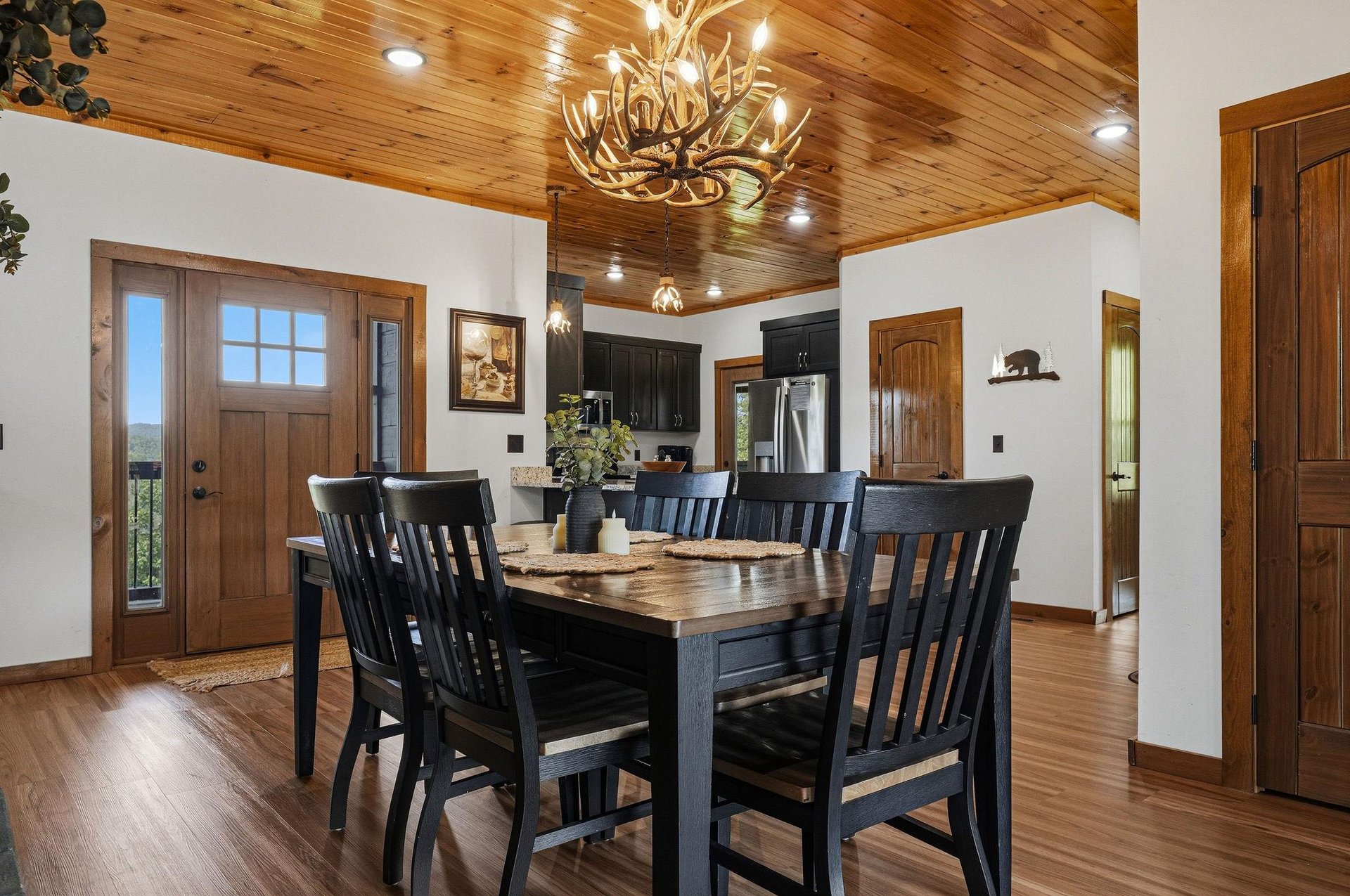 Gather around the handcrafted wood table beneath a stunning antler chandelier. Natural light streams through the entry, highlighting warm wood ceilings and mountaininspired touches throughout your op
