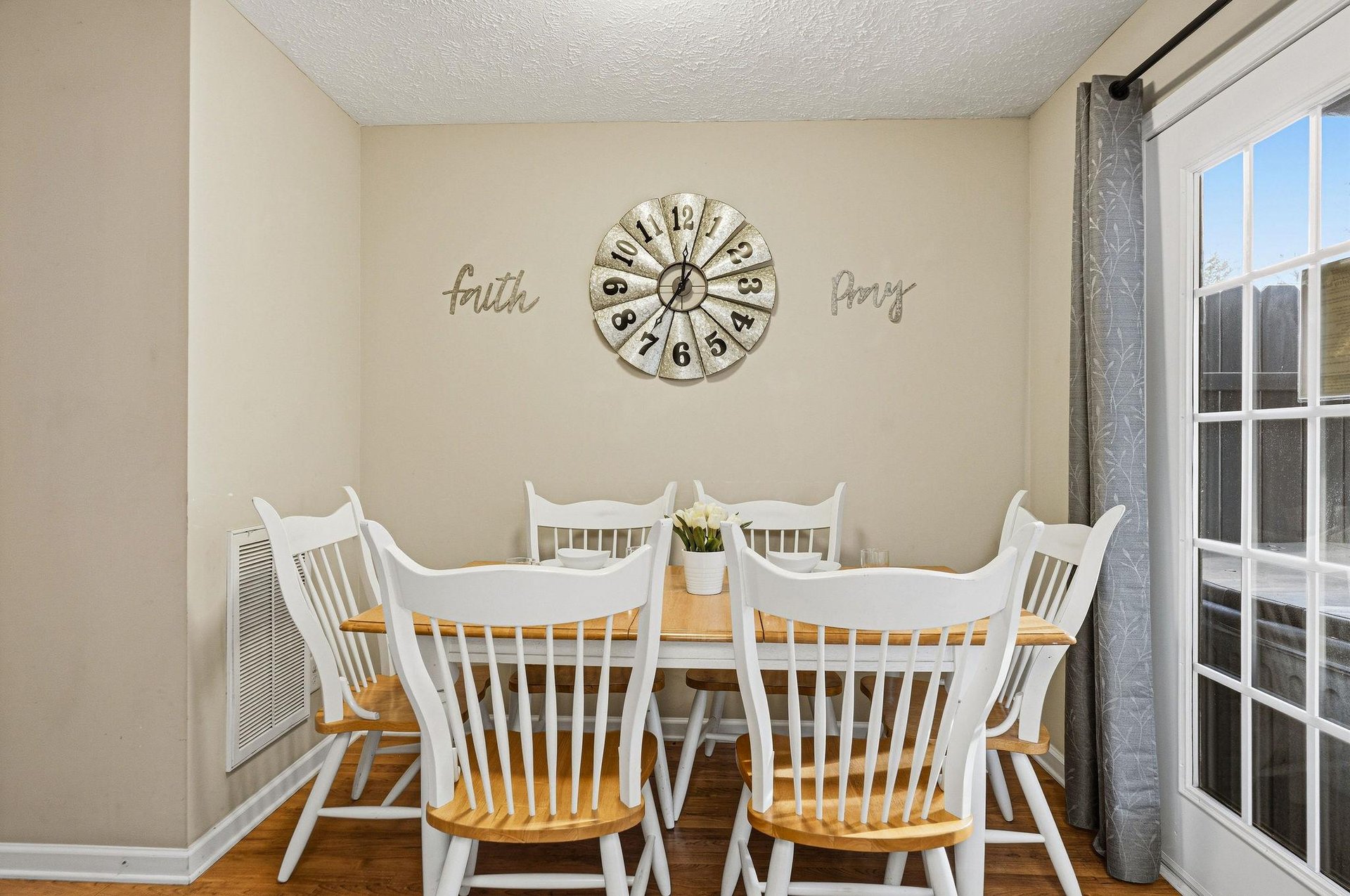 Your charming dining space awaits with vintage farmhouse touches, where faith and family gather around the welcoming white table.