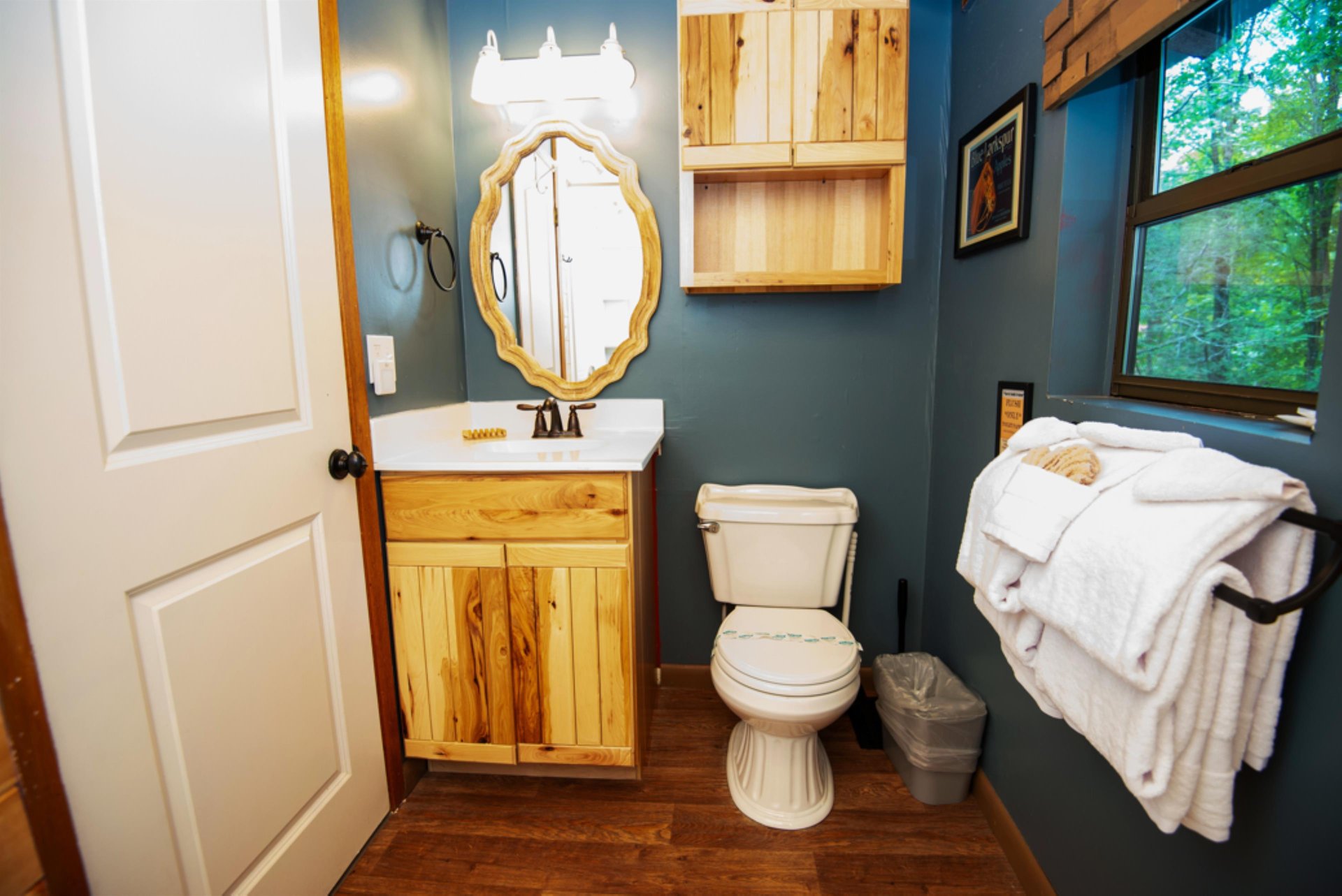 Refresh in your charming rustic bathroom with natural wood vanity, cozy blue walls, and fluffy towels ready for your comfort.