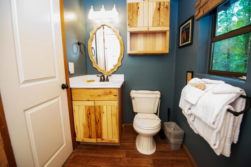 Refresh in your charming rustic bathroom with natural wood vanity, cozy blue walls, and fluffy towels ready for your comfort.