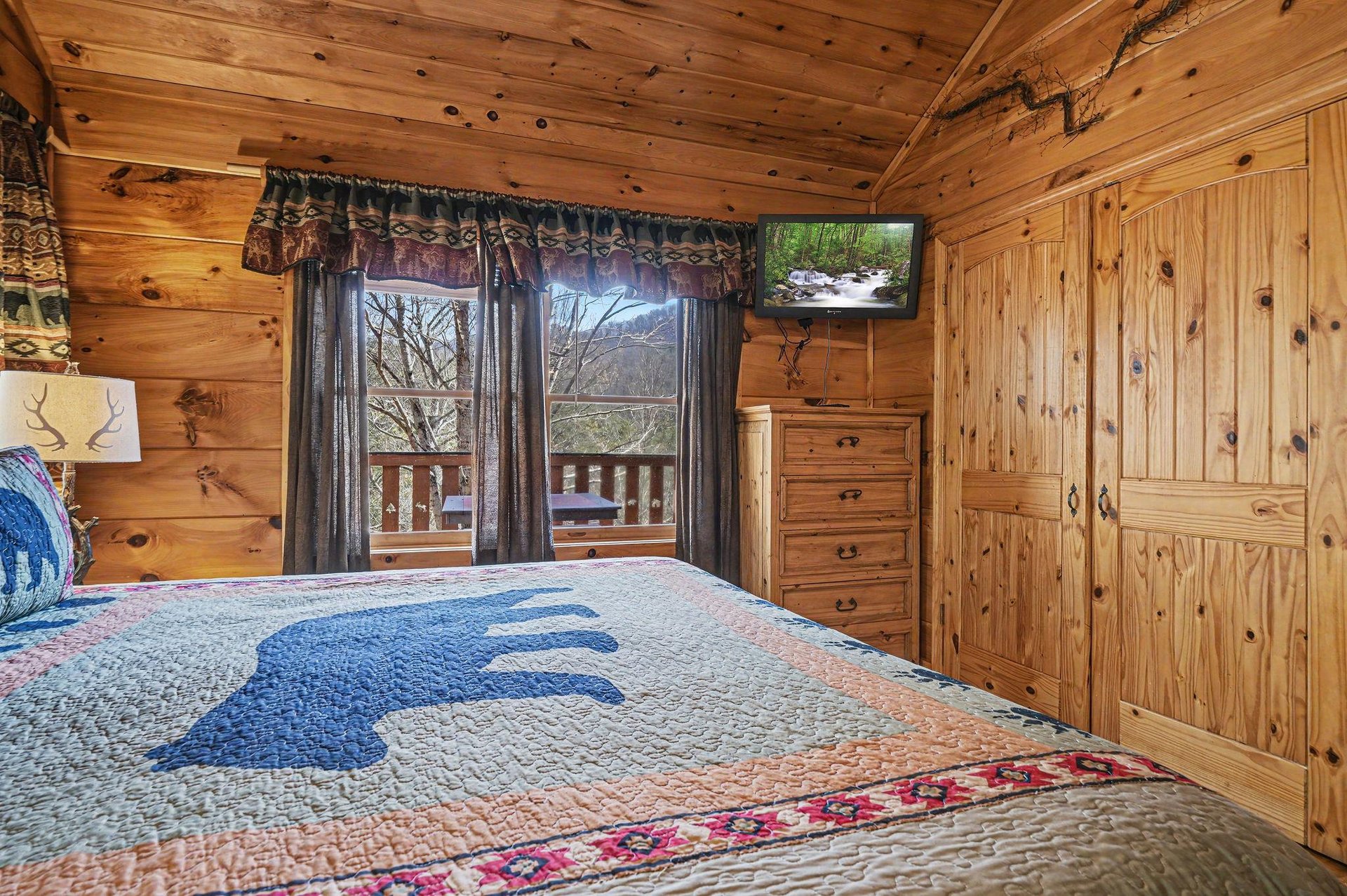 Wake up in your cozy log cabin bedroom surrounded by warm wood and mountain views through your window.