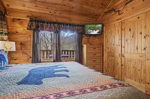 Wake up in your cozy log cabin bedroom surrounded by warm wood and mountain views through your window.