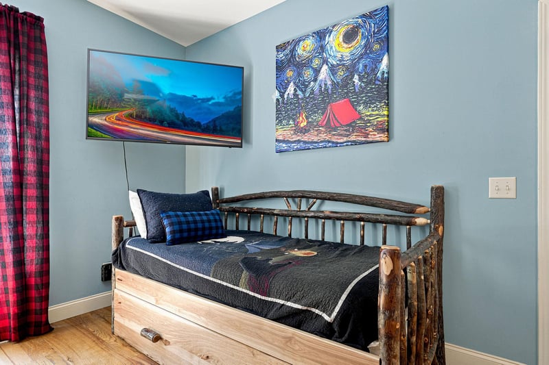 Unwind in your cozy retreat with a rustic log bed, flatscreen TV, and charming artwork. Perfect for restful nights after mountain adventures.