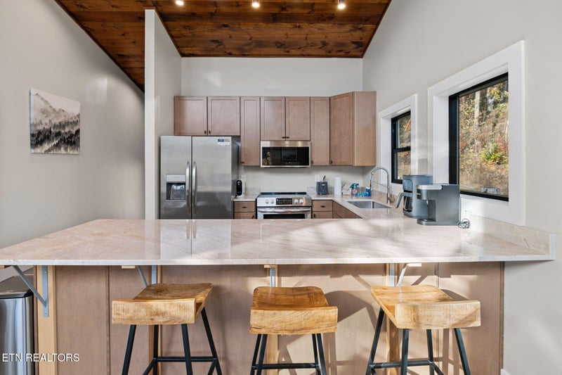 Your modern mountain kitchen awaits with sleek stainless appliances, a spacious island for meal prep, and warm wood touches that bring the outdoors in. Natural light streams through the windows, illum