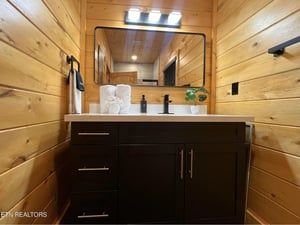 Warm wood surrounds your modern vanity, creating a cozy cabin feel with sleek fixtures and fresh towels ready for your stay.