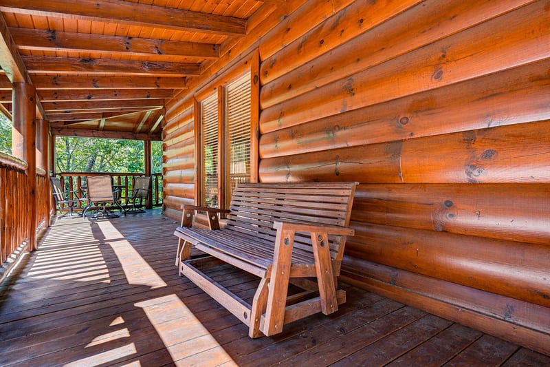 Settle into this rustic porch bench and soak in the peaceful forest views—your private retreat where morning coffee tastes better and worries drift away.