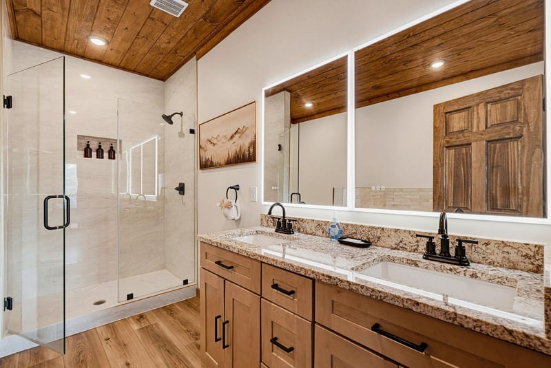 Step into your beautifully designed bathroom featuring a spacious walkin shower, dual vanities, and warm wood accents that create a welcoming mountain retreat ambiance.