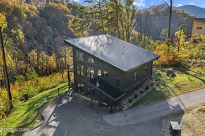 Modern mountain retreat nestled among vibrant autumn foliage, surrounded by towering peaks and serene forest.