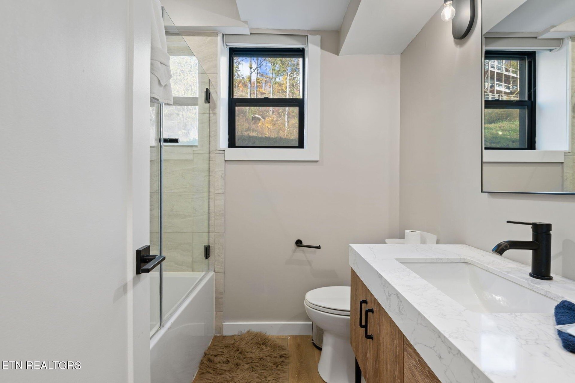 Step into your modern bathroom with a bright, airy feel—natural light through the window, a marbletopped vanity, and a refreshing walkin shower await.