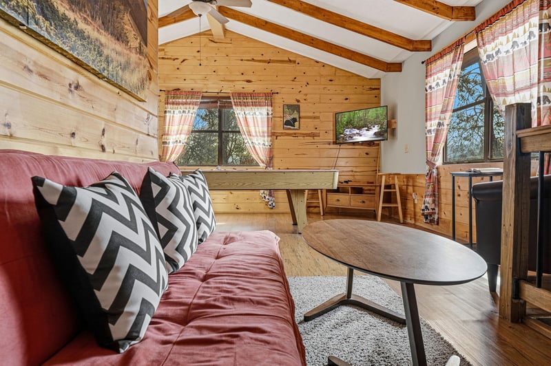 Cozy up in your rustic living space with exposed beams, warm wood walls, and comfortable seating for relaxing mountain evenings.