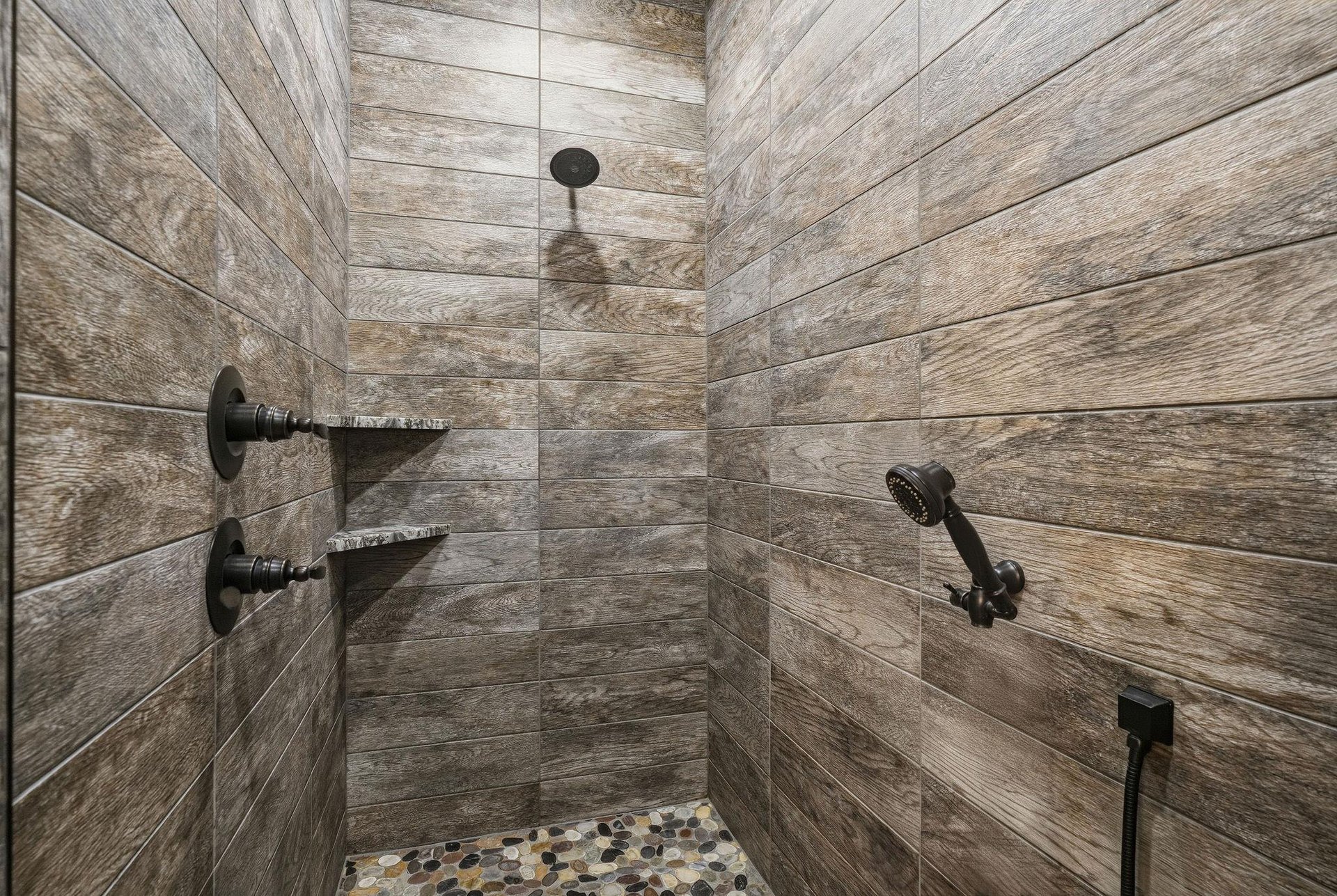 Step into your private spa retreat. Warm woodlook tile wraps around you while dual rainfall fixtures and a handheld spray promise a soothing, rejuvenating escape.