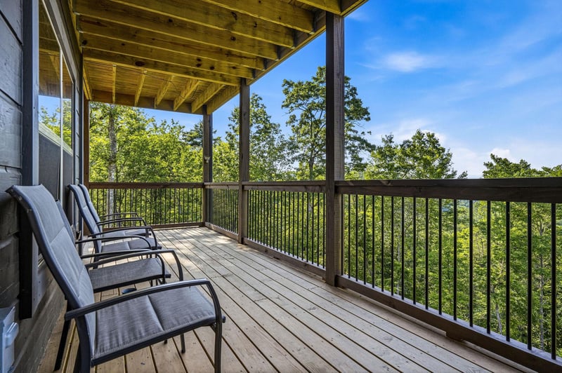 Your covered balcony overlooks a peaceful forest canopy, with comfortable lounge chairs waiting for you to sip morning coffee or unwind as the sun sets beyond the treetops.