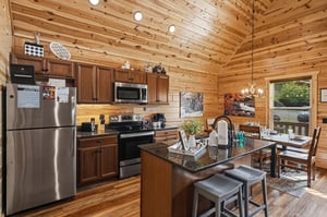 Your mountain retreat features a fullyequipped kitchen with granite counters, stainless appliances, and a cozy island—perfect for gathering over morning coffee or sharing meals surrounded by warm woo