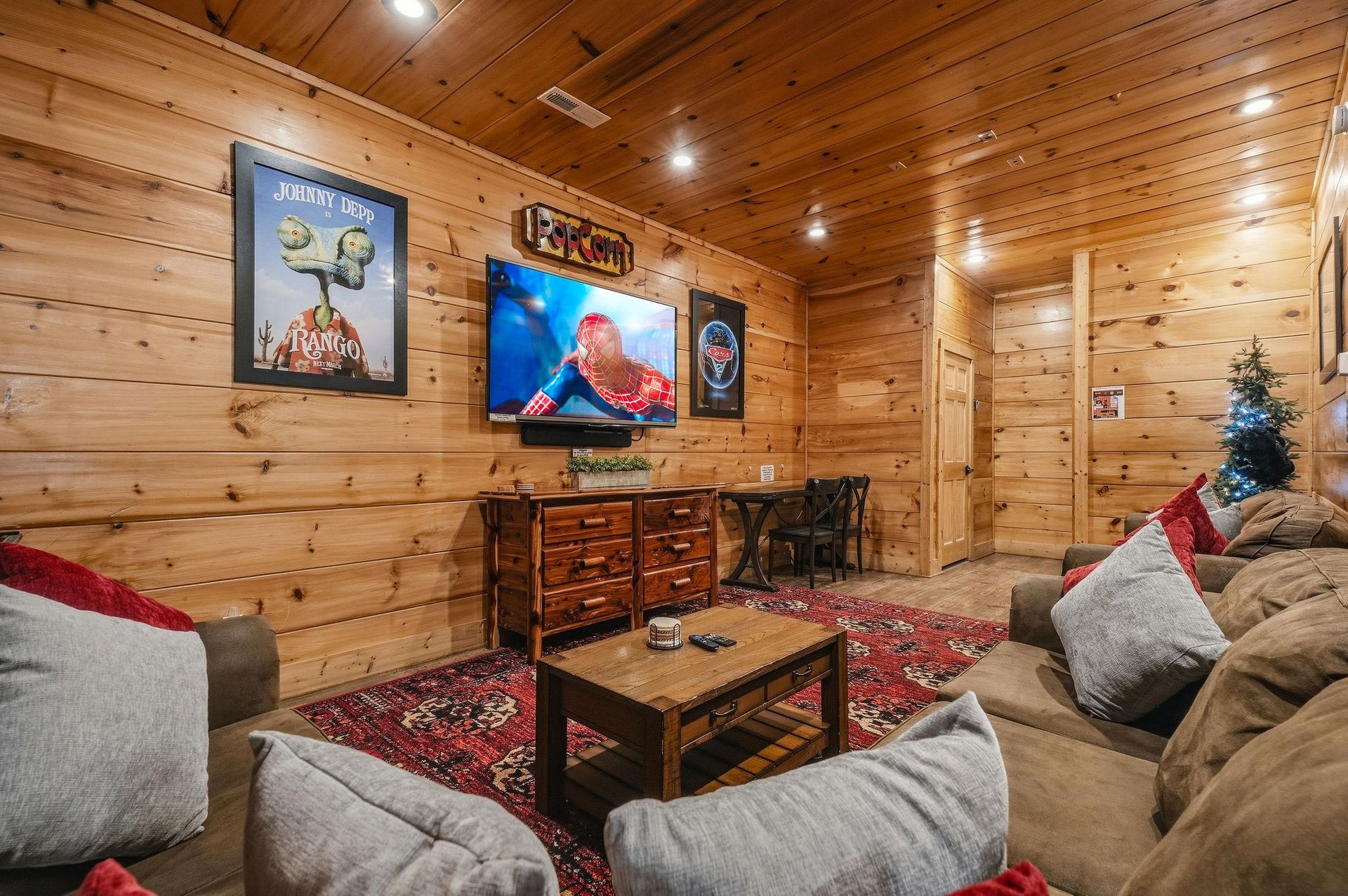 Your private entertainment haven features rich knotty pine walls, plush seating on vibrant rugs, and a cozy atmosphere perfect for movie nights and unwinding with friends.