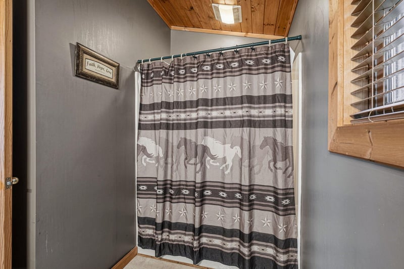 Your private bathroom features a rustic shower with charming Westernthemed curtain and warm wood accents.