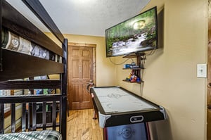 Challenge family and friends to air hockey matches in your dedicated game room with entertainment setup and cozy bunk beds nearby.