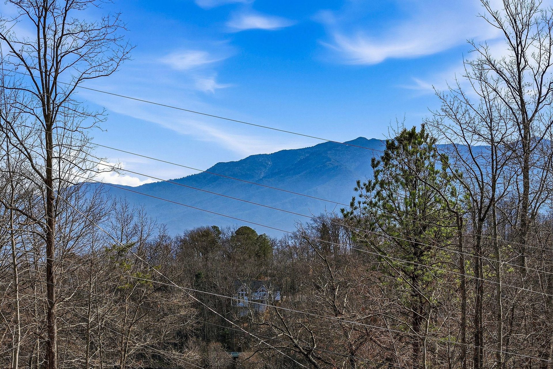 Stunning mountain backdrop frames this peaceful valley setting, with rolling hills and natural forest creating a serene countryside atmosphere.
