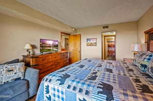 Cozy bedroom with rustic charm featuring naturethemed decor, comfy seating area, and flatscreen TV for your perfect mountain getaway relaxation.