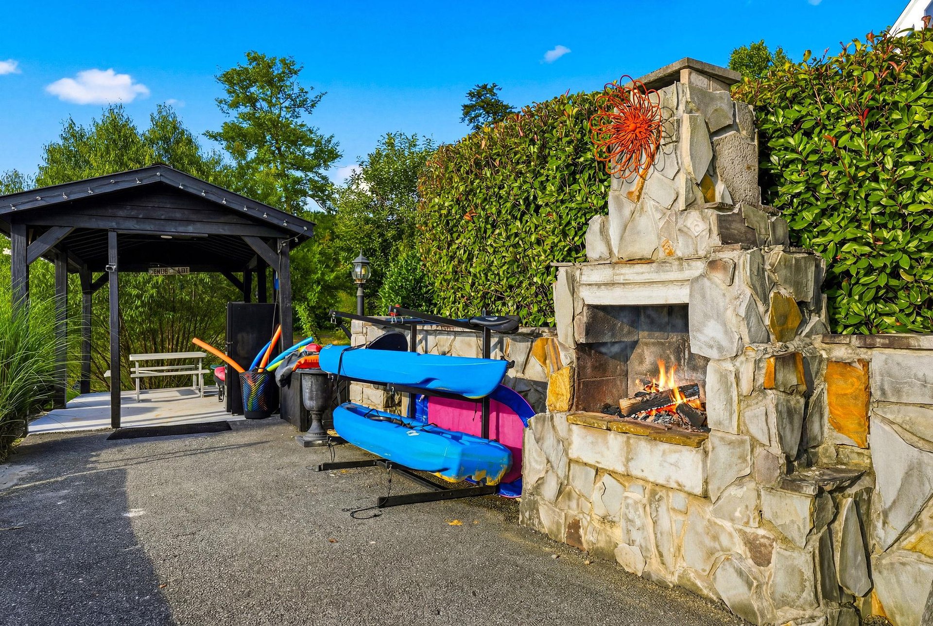 Youll love the outdoor fireplace and kayaks ready for your next adventure on the water, surrounded by lush greenery and blue skies.
