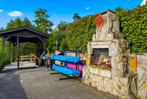 Youll love the outdoor fireplace and kayaks ready for your next adventure on the water, surrounded by lush greenery and blue skies.