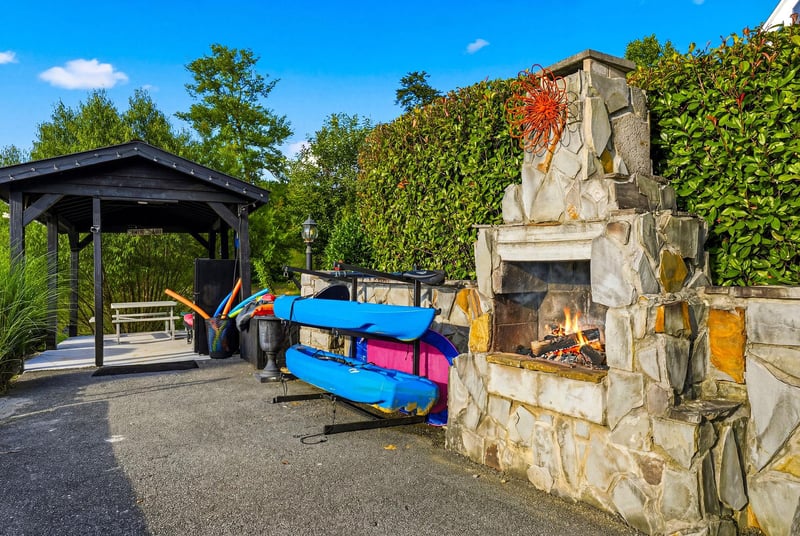 Youll love the outdoor fireplace and kayaks ready for your next adventure on the water, surrounded by lush greenery and blue skies.