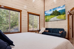 Step into your serene bedroom retreat, where natural light pours through large windows and warm wood walls create a cozy, inviting atmosphere perfect for unwinding after a day of adventure.