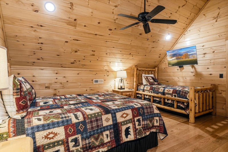 Drift off in this cozy log cabin bedroom, where rustic quilts meet modern comfort beneath warm wood beams and your favorite shows.