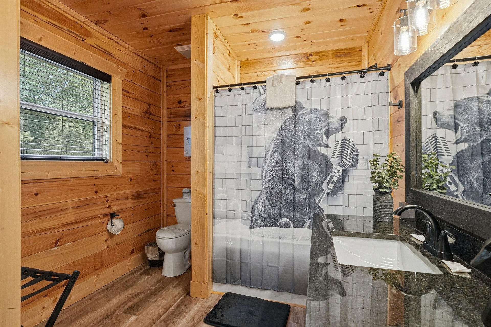 Step into your personal retreat with warm wood walls, a unique bearthemed shower curtain, and a sleek vanity—everything you need to feel refreshed and right at home.