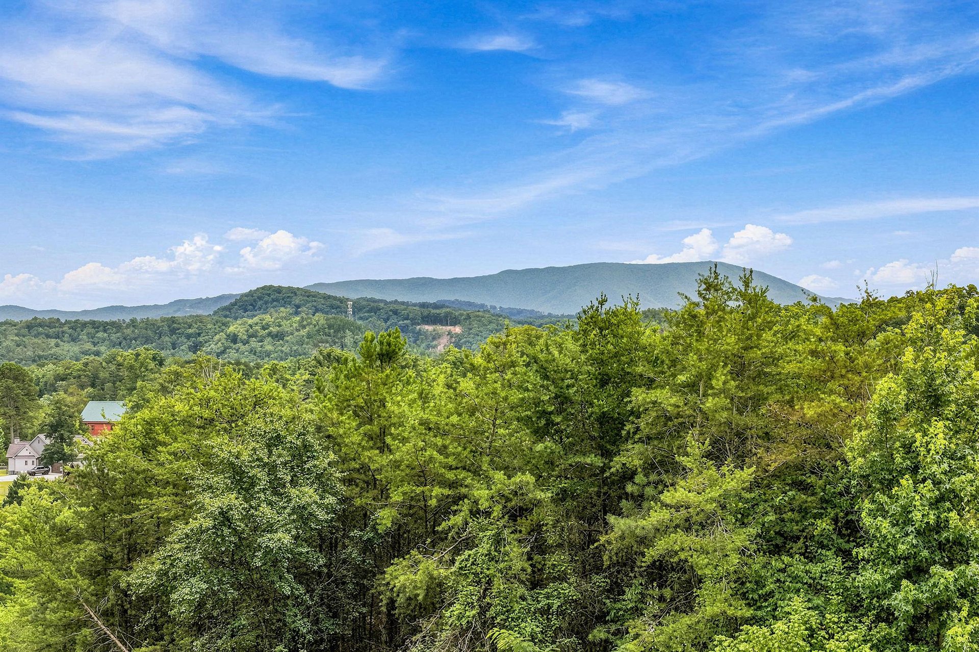 Scenic mountain vistas rise beyond lush green forest, with peaceful countryside visible in the surrounding area.