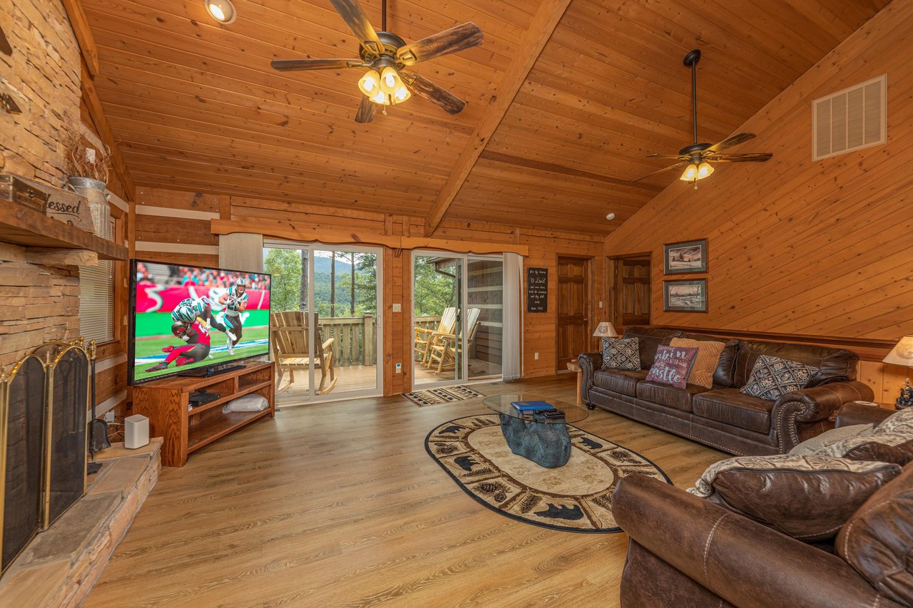 Living room with TV, fireplace, and deck access at Cubs Crib, a 3 bedroom cabin rental located in Gatlinburg