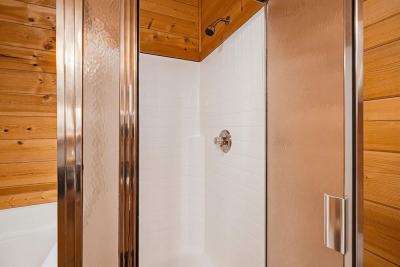 Step into your private shower, where rustic wood meets modern convenience. Crisp white tile and warm pine create a cozy, cabinstyle retreat.