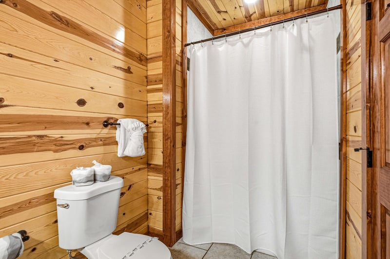 Step into your rustic bathroom with warm wood walls, fresh towels, and a spacious shower for your mountain retreat comfort.