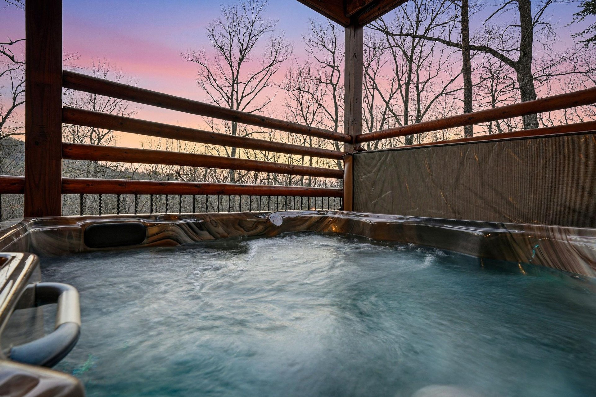 Soak in your private hot tub as twilight paints the sky in soft purples and pinks, surrounded by peaceful bare trees.