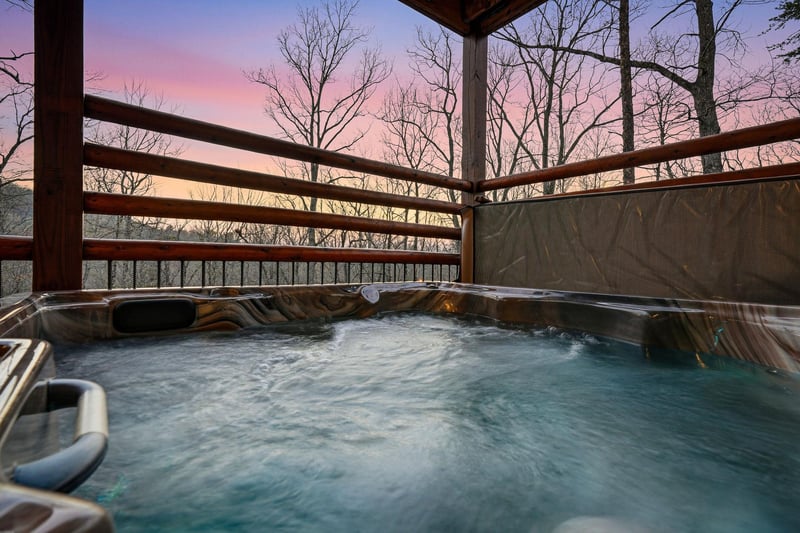 Soak in your private hot tub as twilight paints the sky in soft purples and pinks, surrounded by peaceful bare trees.