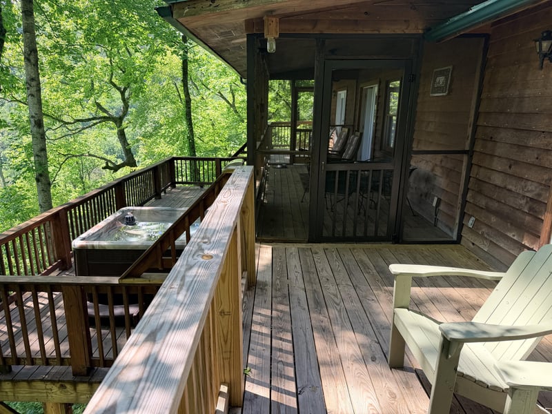 Unwind on your private deck surrounded by lush forest views, where a soothing hot tub and cozy seating invite peaceful mornings and starlit evenings in nature.
