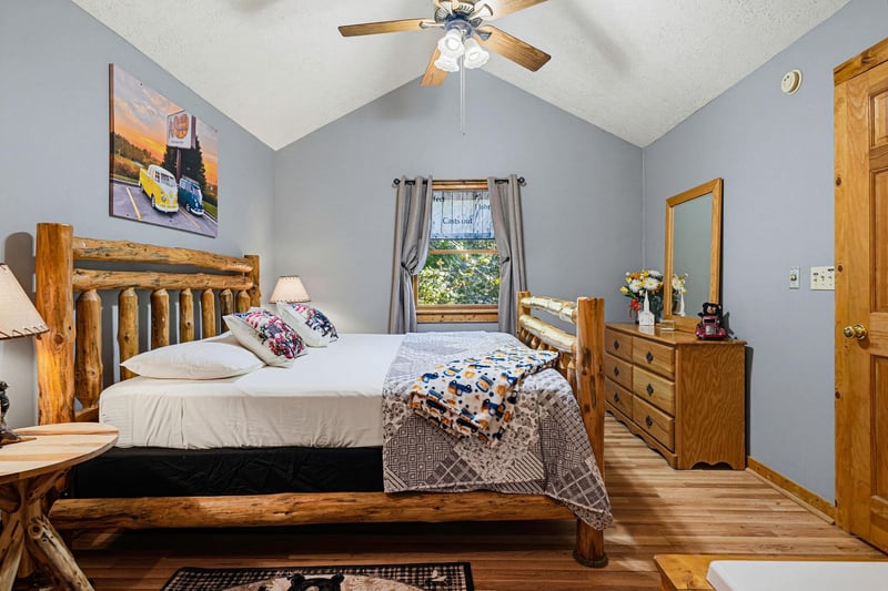 Your cozy bedroom with rustic log furniture and vaulted ceilings invites restful nights, while natural light streams through the window for peaceful mornings.