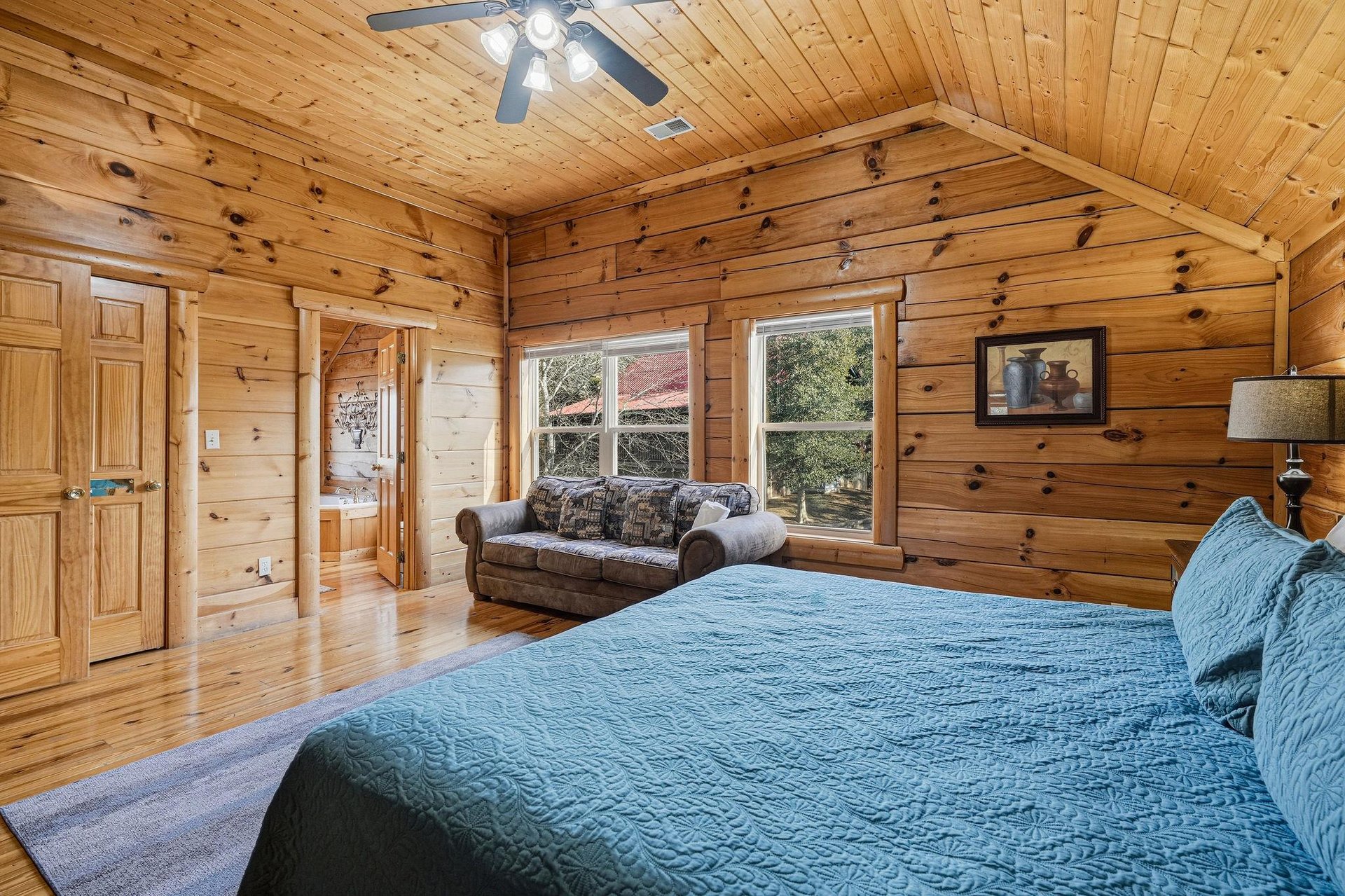 Drift off in this cozy cabin bedroom where rustic wood walls create warmth while you enjoy treetop views from your comfortable bed.