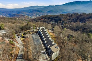 Aerial view of a modern mountain retreat nestled among rolling hills, offering stunning Blue Ridge Mountain vistas and peaceful surroundings.