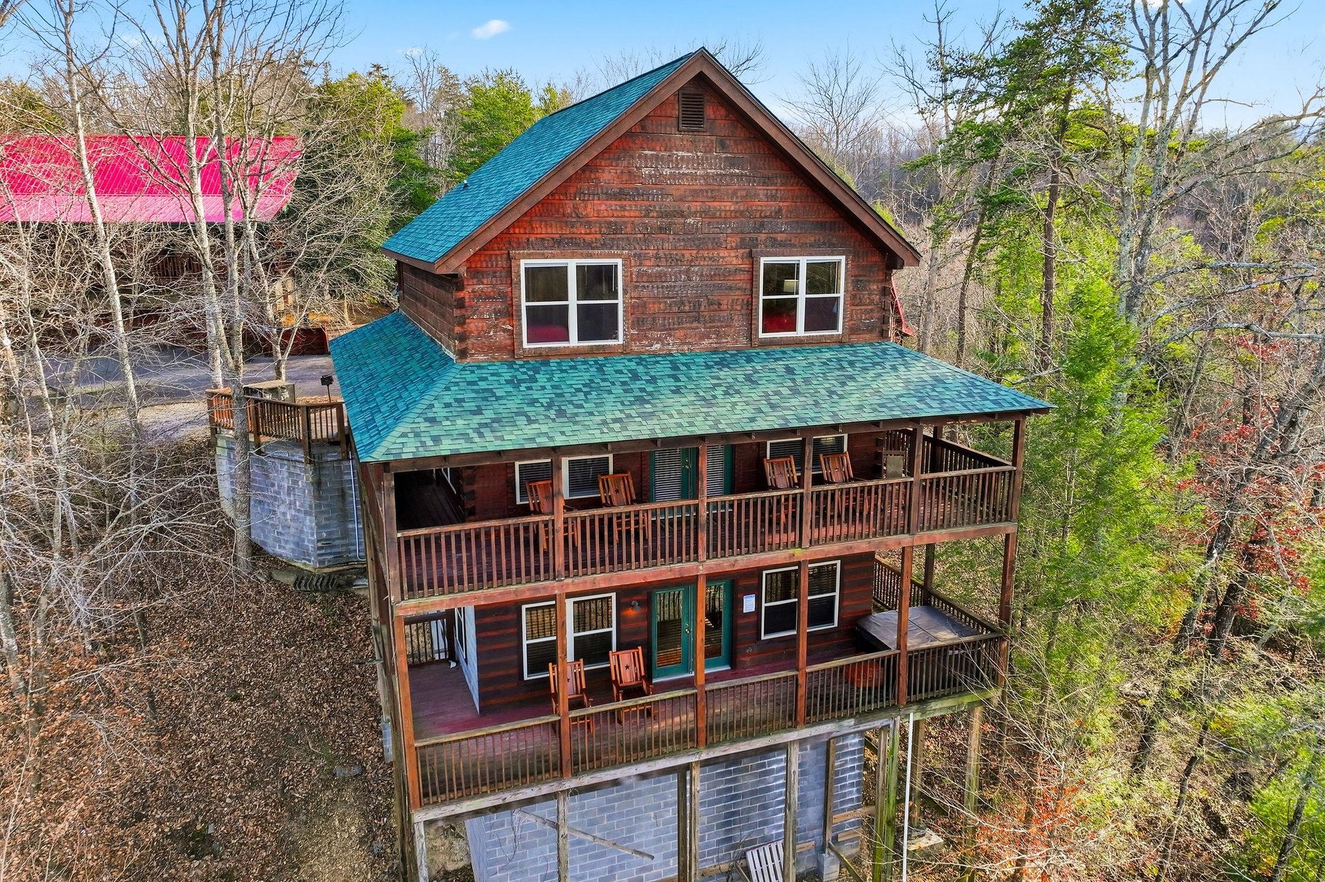 Mountain cabin retreat featuring multiple decks surrounded by wooded landscape, offering peaceful forest views and rustic charm.