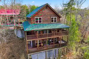 Mountain cabin retreat featuring multiple decks surrounded by wooded landscape, offering peaceful forest views and rustic charm.