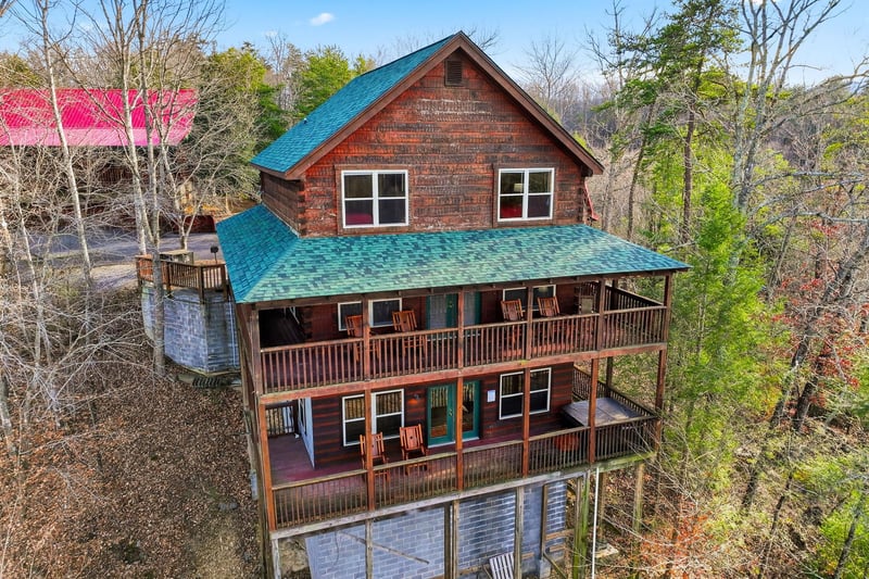 Mountain cabin retreat featuring multiple decks surrounded by wooded landscape, offering peaceful forest views and rustic charm.