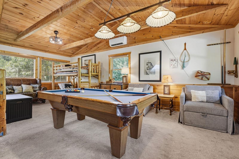 Your ultimate game room awaits with vaulted wood ceilings, cozy seating, and a billiard table ready for friendly competition. Relax between rounds on the plush sofas or challenge the family to a tourn